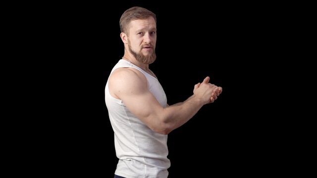 Caucasian sporty man stands sideways in a tank top on a black background. One man is a model. High quality photo