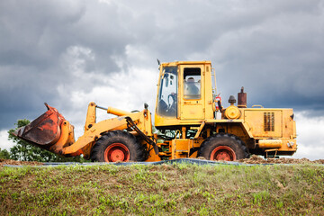 Obraz na płótnie Canvas A yellow bulldozer at work, high on a hill.
