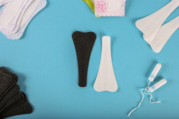 Choice between black or white pad. Menstrual tampons and pads on a blue background. Menstruation cycle. Hygiene and protection. Flat lay. With copy space for text.