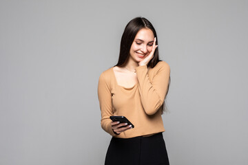 Naklejka premium Portrait of a smiling casual woman holding smartphone remember something over white background