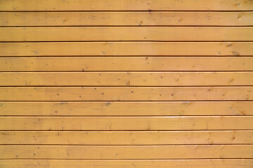 Texture of an edge siding made of painted in beige panels with multiple knots as a background