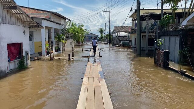 Woman walk through a wooden footbridge set up above a flooded street in Careiro da Varzea, near Manaus (AM), during the rise of Negro River due to heavy rains in Brazil.