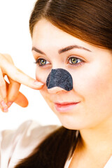 Woman applying pore strips on nose