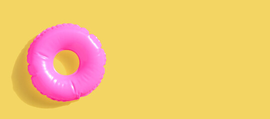 Pink inflatable swimming pool ring on yellow surface