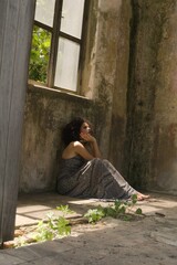 Brazilian woman with afro hair in a dress in a destroyed house