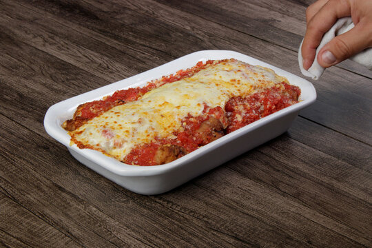 Steak Parmegiana or Parmegian Filet, made with breaded steak, tomato sauce, mozzarella cheese and Parmesan cheese. Hand beside holding napkin.