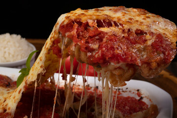 Steak Parmegiana or Parmegian Filet, made with breaded steak, tomato sauce, cheese au gratin. Serving piece with melted cheese. Close-up photography.