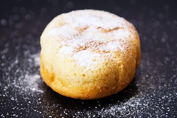 Sweet juicy muffins sprinkled with vanilla sugar on a black plate