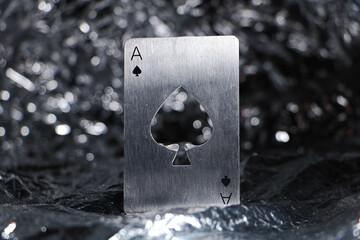 Closeup shot of an ace of spades metallic card isolated on the silver, bokeh background