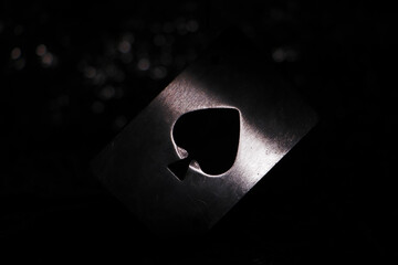 Closeup shot of an ace of spades metallic card isolated on the black background - shadow