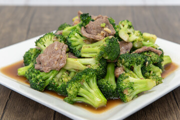 Large pile of spicy Thai broccoli served with meat and sauce on a plate
