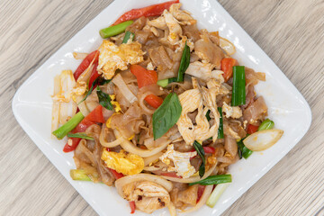 Overhead view of big noodles stir fry with basil on top of pile of vegetables for that delicious spicy Thai flavor