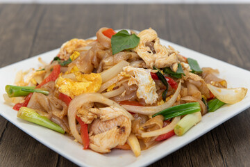 Big noodles stir fry with basil on top of pile of vegetables for that delicious spicy Thai flavor
