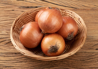 Onions in a basket over wooden table