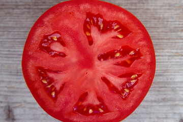 Fresh cuted tomato on a grey wooden board close up. Healthy food background. Juicy summer red vegetable on the table.