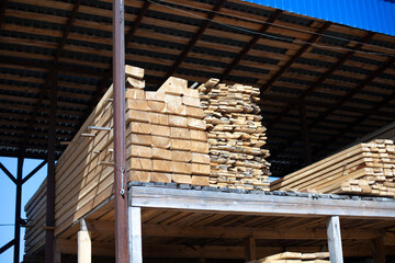 Lots of boards in the warehouse. Bars of wood are stacked.