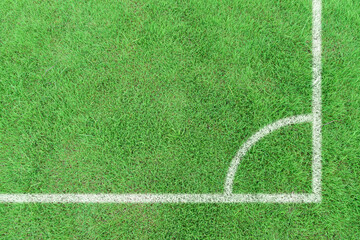 White stripe corner markings on a football field with green grass. Top view sport background.