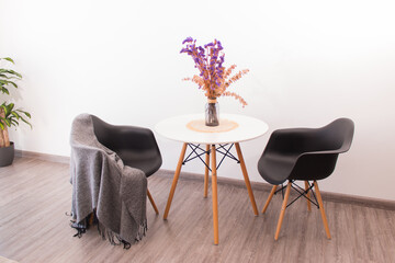 Fototapeta premium Decoración minimalista al estilo nórdico con naturaleza muerta y flores sobre mesas y sofá