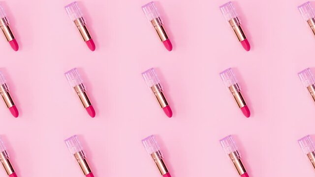 Make up pattern made of pink lipsticks rotate on bright pink background. Stop motion