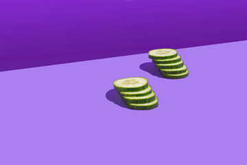 Sliced cucumbers forming a ladder on a purple background. Pop style. Copy space