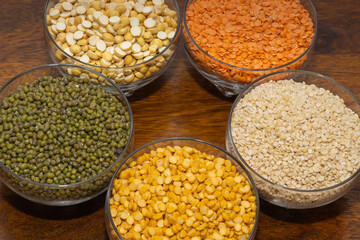 Assorted variety of lentils kept in different bowls on a wooden table
