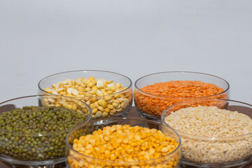 Side view of assorted varieties   lentils kept in different bowls with plain background 