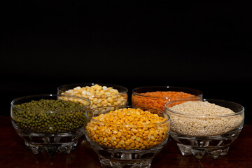 Side view of assorted varieties   lentils kept in different bowls with plain background 