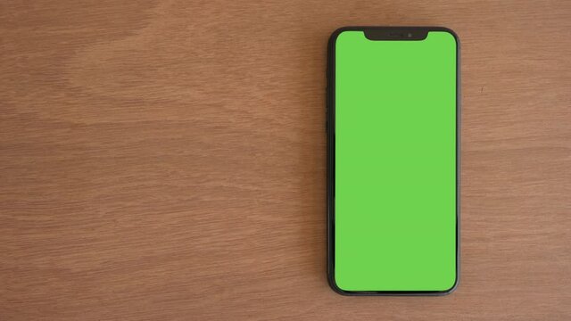 Smartphone place on wood table, Green screen telephone, Close up display mobile phone with mock up, Chroma key monitor, Close-up the cell phone on brown desktop, Mockup smartphone, Slider top view.  