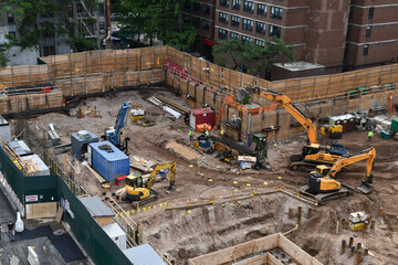 Excavators digging on skyscraper construction site with foundation pit - 436954512