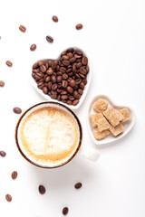 Mug with coffee and heart shaped plates with coffee beans and brown sugar. Top view. Vertical photo