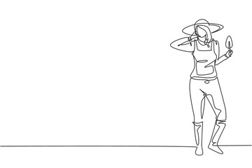 Single continuous line drawing female farmer stood with call me gesture, wearing straw hat and carrying mini shovel to plant crops on farmland. Dynamic one line draw graphic design vector illustration