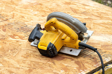 close up of a yellow electric circular saw on wooden bord