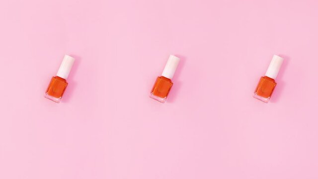 Three nail polishes bottles rotate on pastel pink background. Stop motion