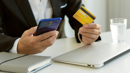 Businessmen hold credit cards and use laptop computers and mobile phones for online purchases, ecommerce, internet banking. spend money through the internet