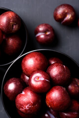 Japanese or Chinese red plum fruit in a bowl on black background, Top view	