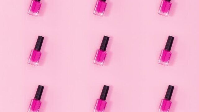 Beauty concept pattern made of nail polishes bottles in same color rotate on bright pink theme. Stop motion
