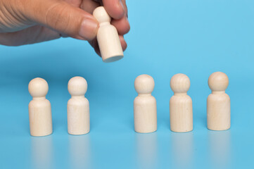 Hands grab a wooden doll figure from the group of workers. Firing someone concept