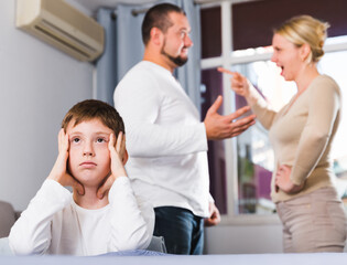 Fototapeta premium Sad desperate little boy during parents quarrel in home interior