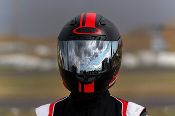A  Racer's visor reflects a cloudy sky after a light rain between races