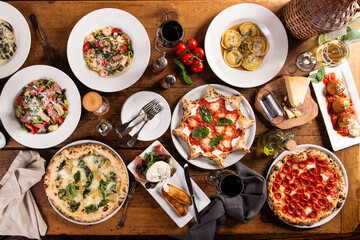 Big dinner table with italian food, pizzas and pastas - obrazy, fototapety, plakaty