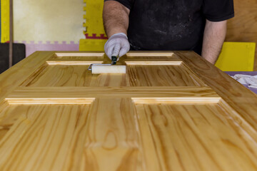 Contractor painter varnished of painting doors using hand roller varnish with gloves