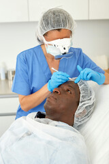 Fototapeta premium Cosmetician female in mask is preparing client for mesotherapy in beauty clinic