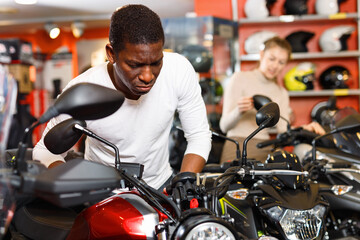 Portrait of young happy smiling man buying new motorcycle at modern showroom