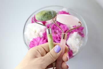 Green jade roller and pink face roller laying on the gift box 8 march. Beauty tools.	