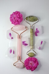 Green jade roller and pink face roller laying on the gift box 8 march. Beauty tools.	