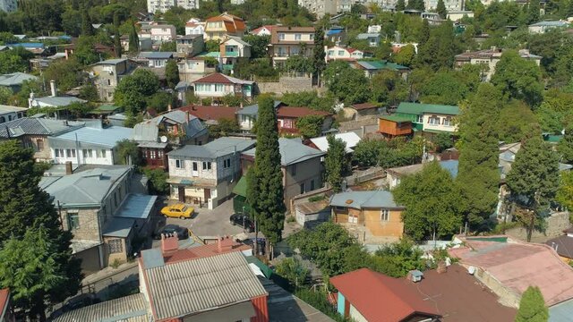 Aerail cinematic cityscape Yalta Crimea close-up village details. Old hotels houses mountainside. Real life population housing. Small courtyards, old Lada cars. Summer seaside resort Ukraine old town