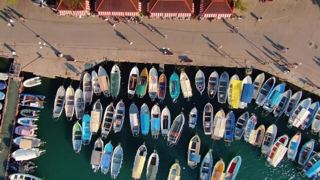 Aerial resort seaside town promenade embankment, people tourists walking. Many beautiful multicolored motorboat boats on pier pettern top down view. Greece Crimea Ukraine abstract. Summer stock movie