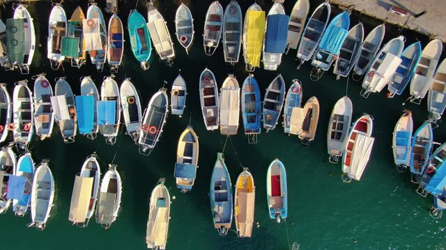 Drone top down abstract marina harbor many colorful boats authentic ships fishing boats on shore near embankment of resort town. People tourists walk. Beautiful city details. Marine vessels pattern