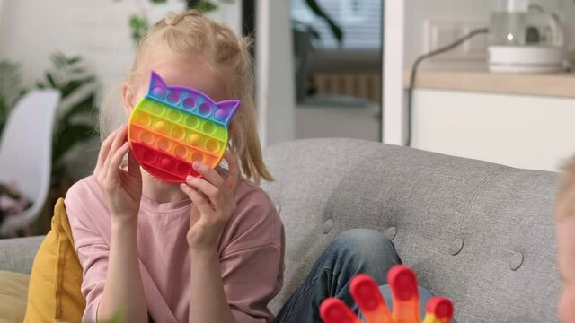Kids playing with colorful silicone sensory fidget toy, boy and girl pressing soft rainbow bubbles for stress and anxiety relief, modern relaxation and focus game