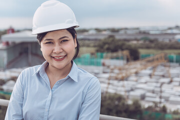 Female Civil Engineer in Safety Hard Hat Standing Against With Construction Site Background. Portrait of Professional Construction Engineer During Working at Building Project Site. Job Occupation